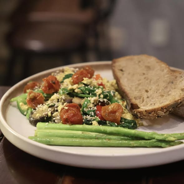 Scrambled eggs with spinach, tomatoes, asparagus and seeded bread