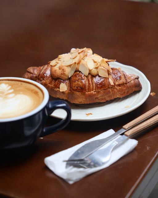 Almond croissant served beside a cappuccino